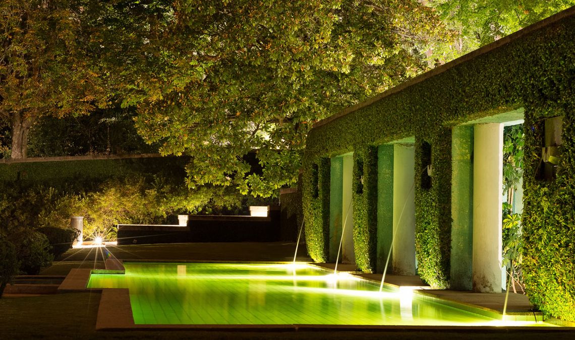 Quiet fountain and swimming pool in a modern architecture house. The long exposure enhances the light and the green colour of the foliage