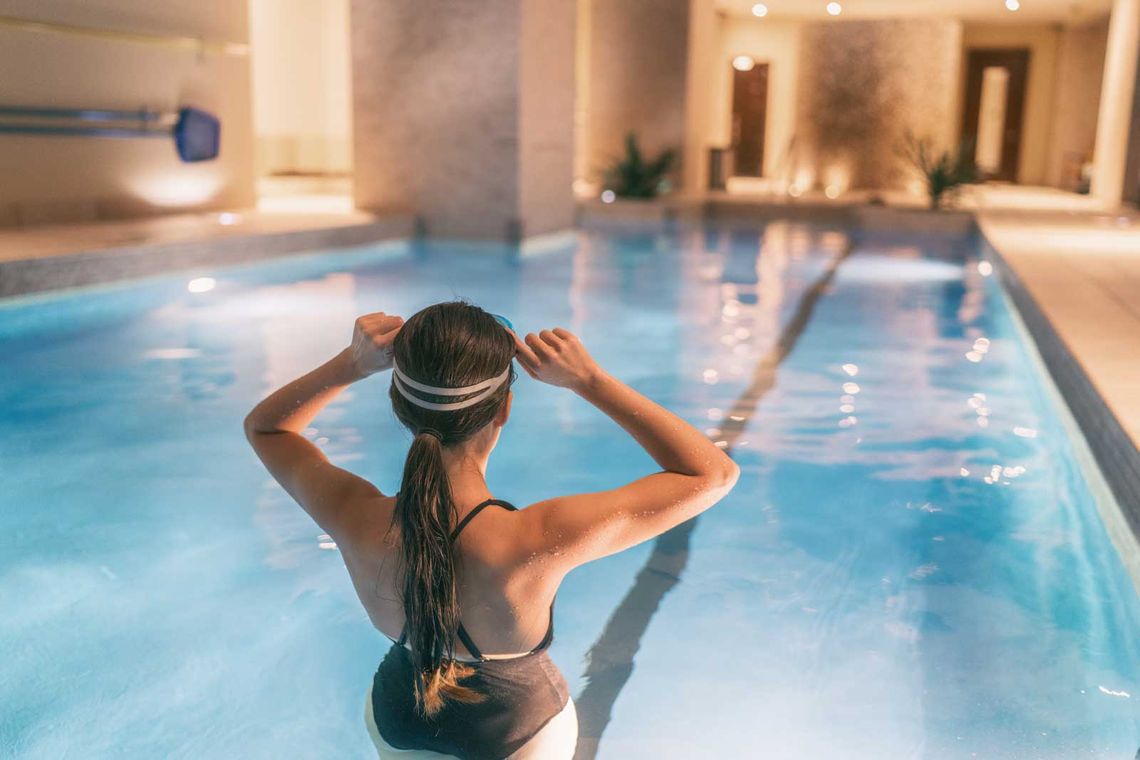 Woman getting ready to swim in indoor swimming pool at hotel or apartment building complex